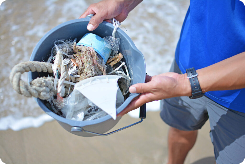 手にしたバケツいっぱいに、プラスチックの破片や漁具などが入っている。